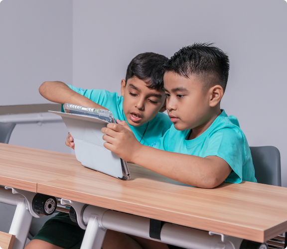 Two boys having an ongoing discussion through the use of a tablet.